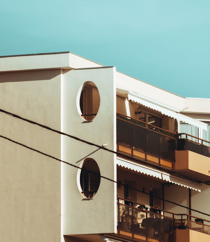 A modern apartment building featuring balconies under a clear blue sky.